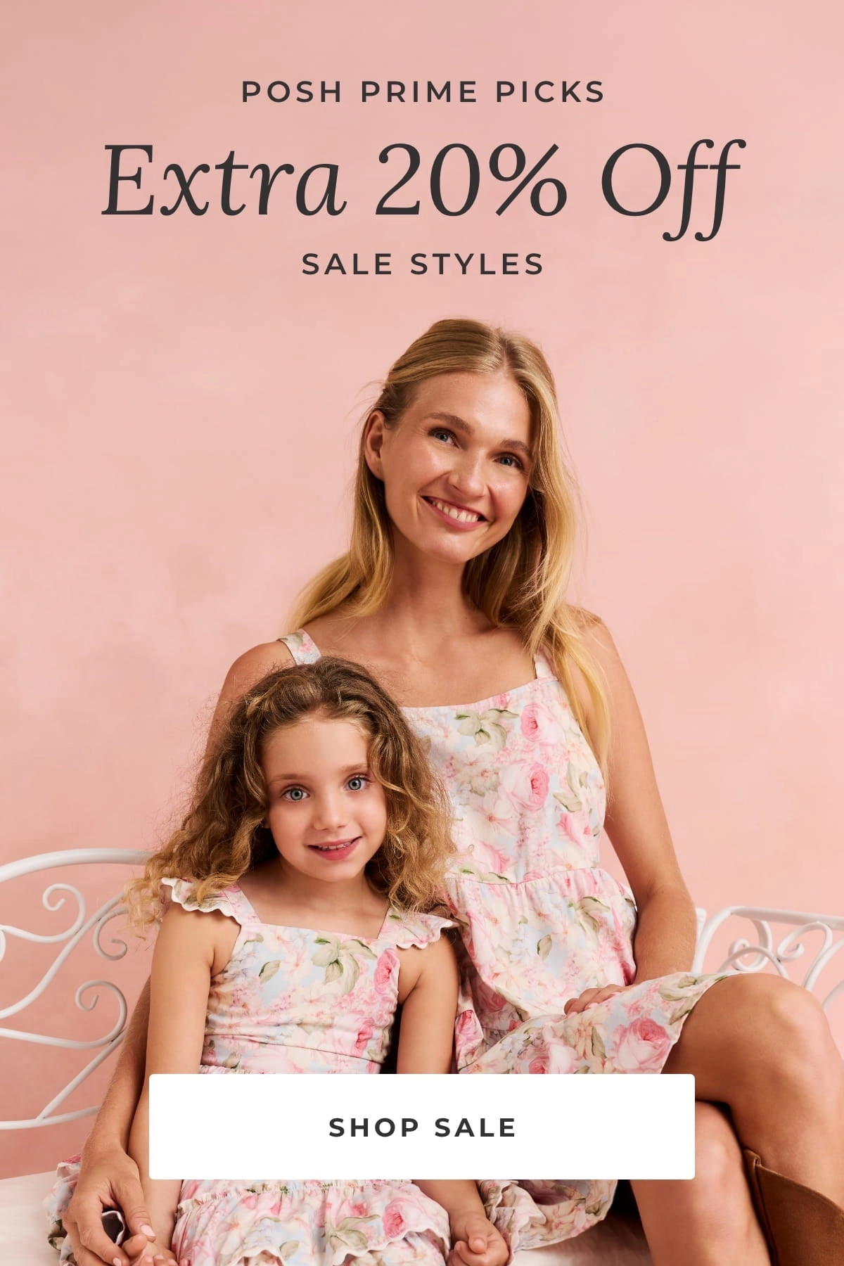 Mother and daughter in matching floral dresses sitting on a white bench