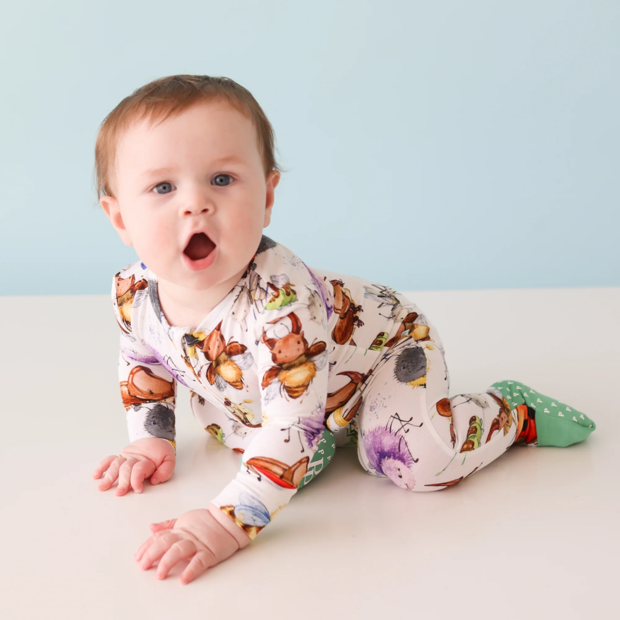 Baby boy wearing one piece with printed bugs and critters